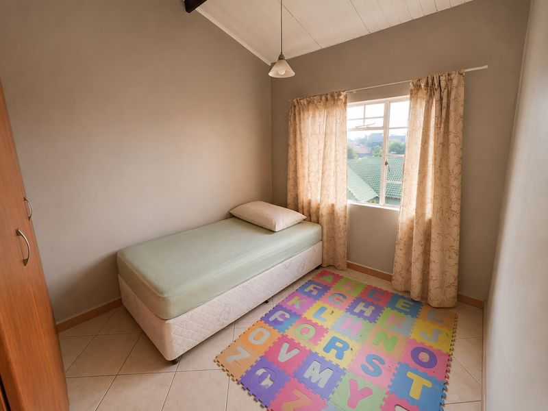 A compact bedroom featuring tiled flooring, a built-in wardrobe, and an exposed beam ceiling, offering a functional space with natural light.