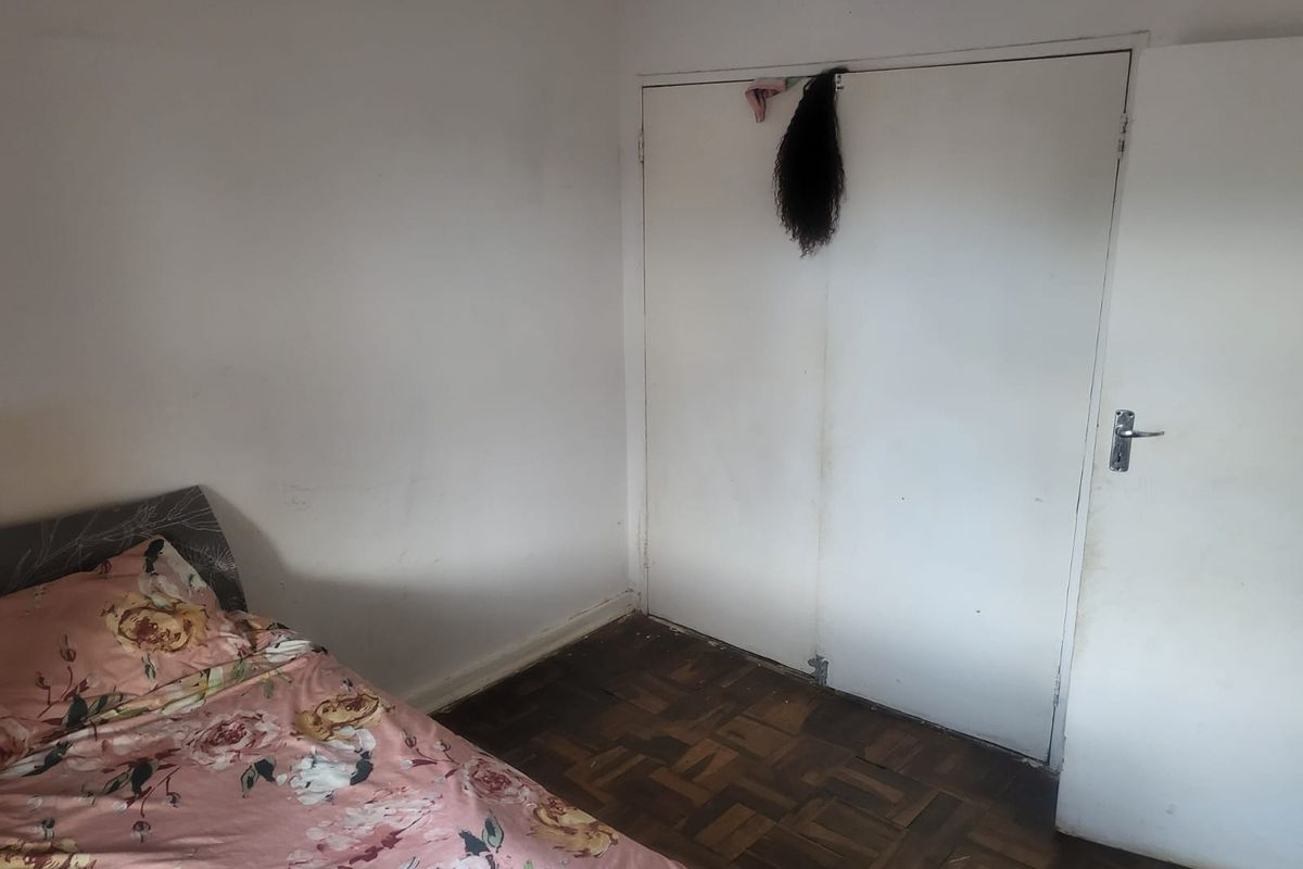 A bedroom featuring original parquet flooring and built-in cupboard storage, requiring cosmetic updates to walls and floor finishes.