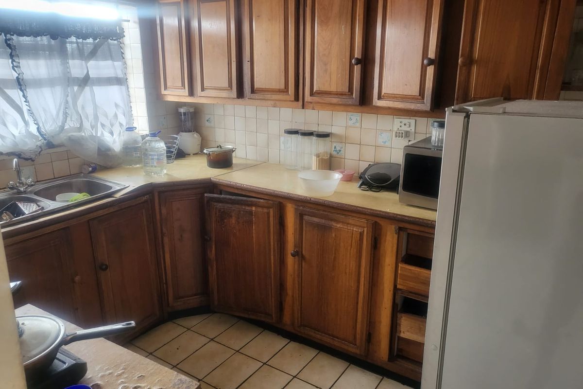 A dated kitchen featuring traditional wooden cabinetry, tiled backsplash, and laminate countertops, offering significant potential for a modern renovation.