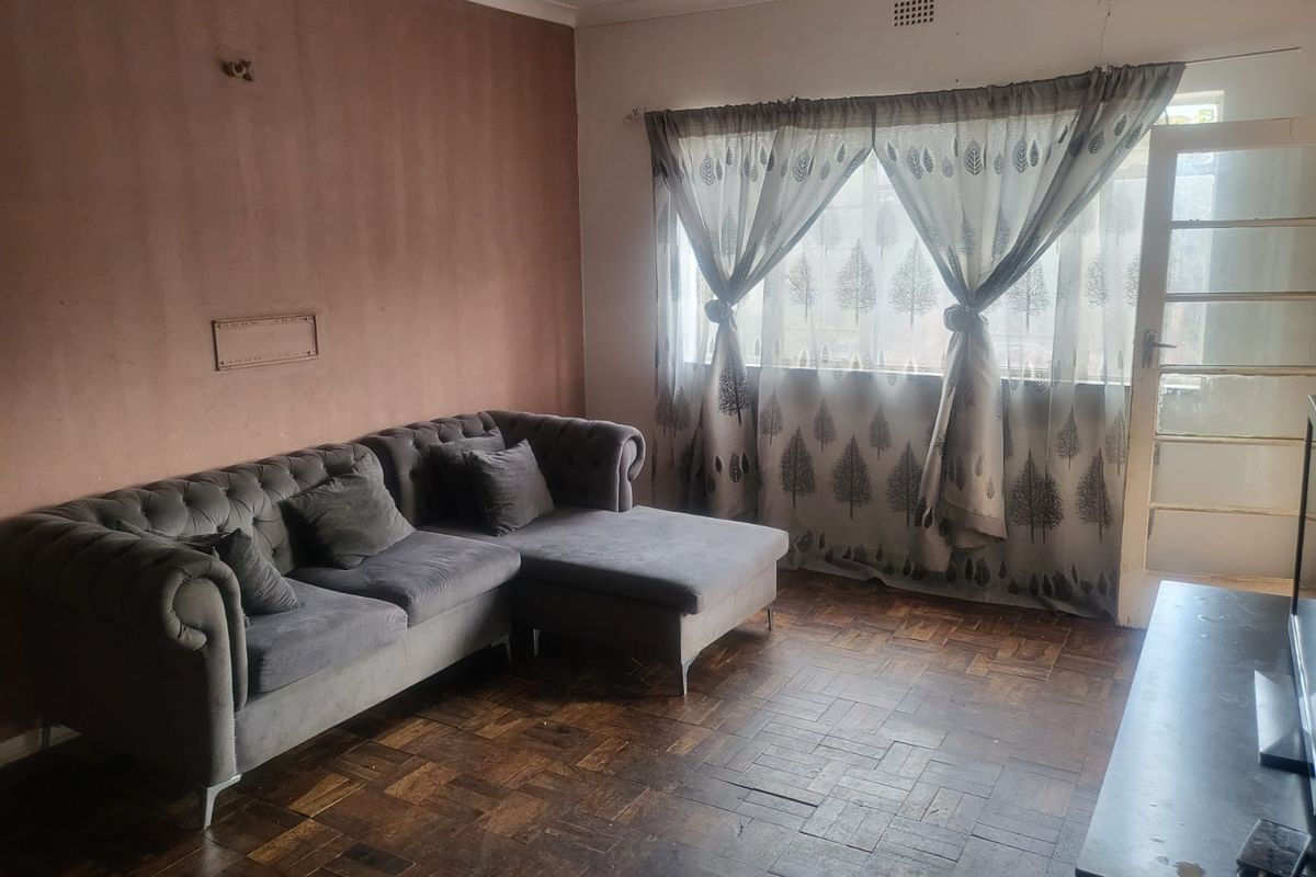 A living room featuring original parquet flooring, a glass panel door, and coved ceilings, offering a blank canvas for renovation and modernization.