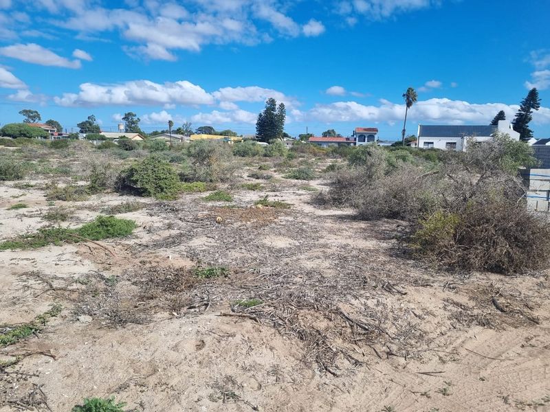 An undeveloped plot of land featuring natural sandy terrain and wild shrubbery, offering a blank canvas for future landscaping or construction projects.