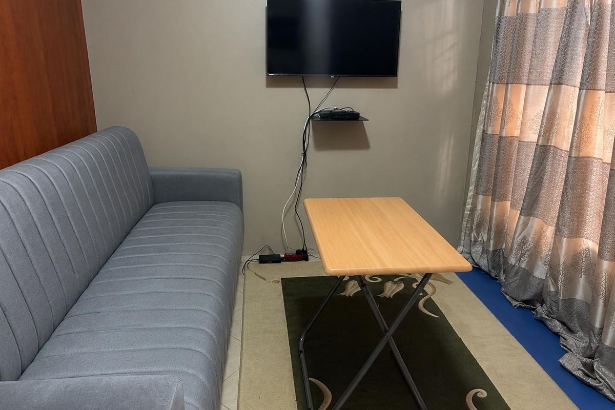 A compact living area featuring a wall-mounted television and neutral wall finishes, suitable for a small apartment layout.