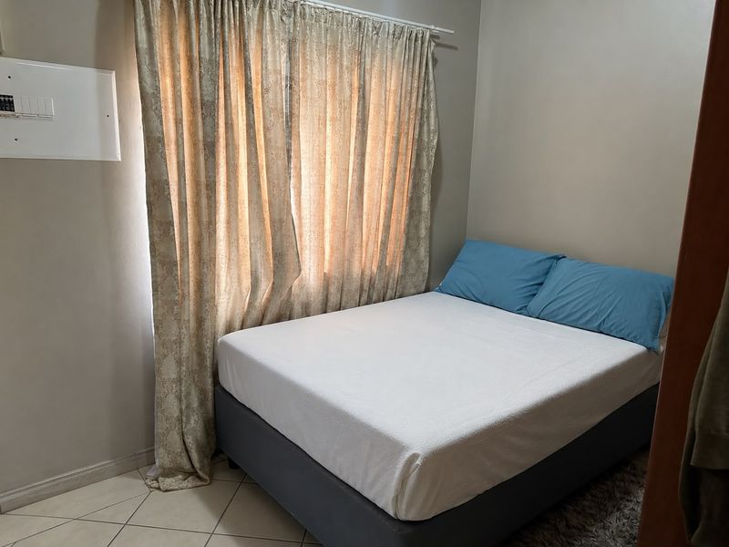 A compact bedroom featuring tiled flooring and a wall-mounted electrical distribution board, providing a functional space for rest.