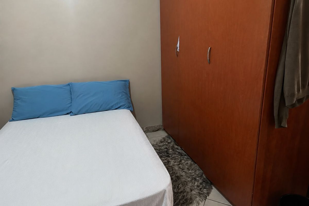 A bedroom featuring a large built-in wooden wardrobe and tiled flooring.