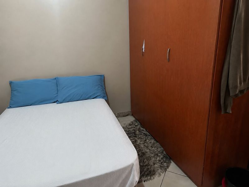 A bedroom featuring a large built-in wooden wardrobe and tiled flooring.