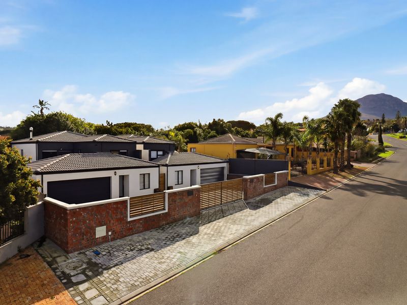 Aerial view of the property showcasing the modern exterior, tiled roof, secure brick boundary wall with timber fencing, and paved driveway access.
