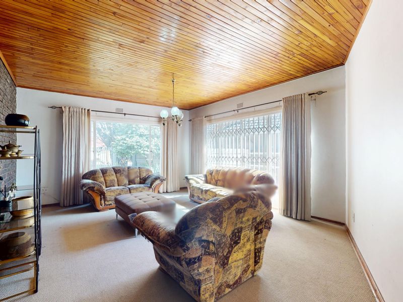 Spacious living room featuring a distinctive timber tongue and groove ceiling, an exposed brick feature wall, and large sliding doors leading to the exterior.