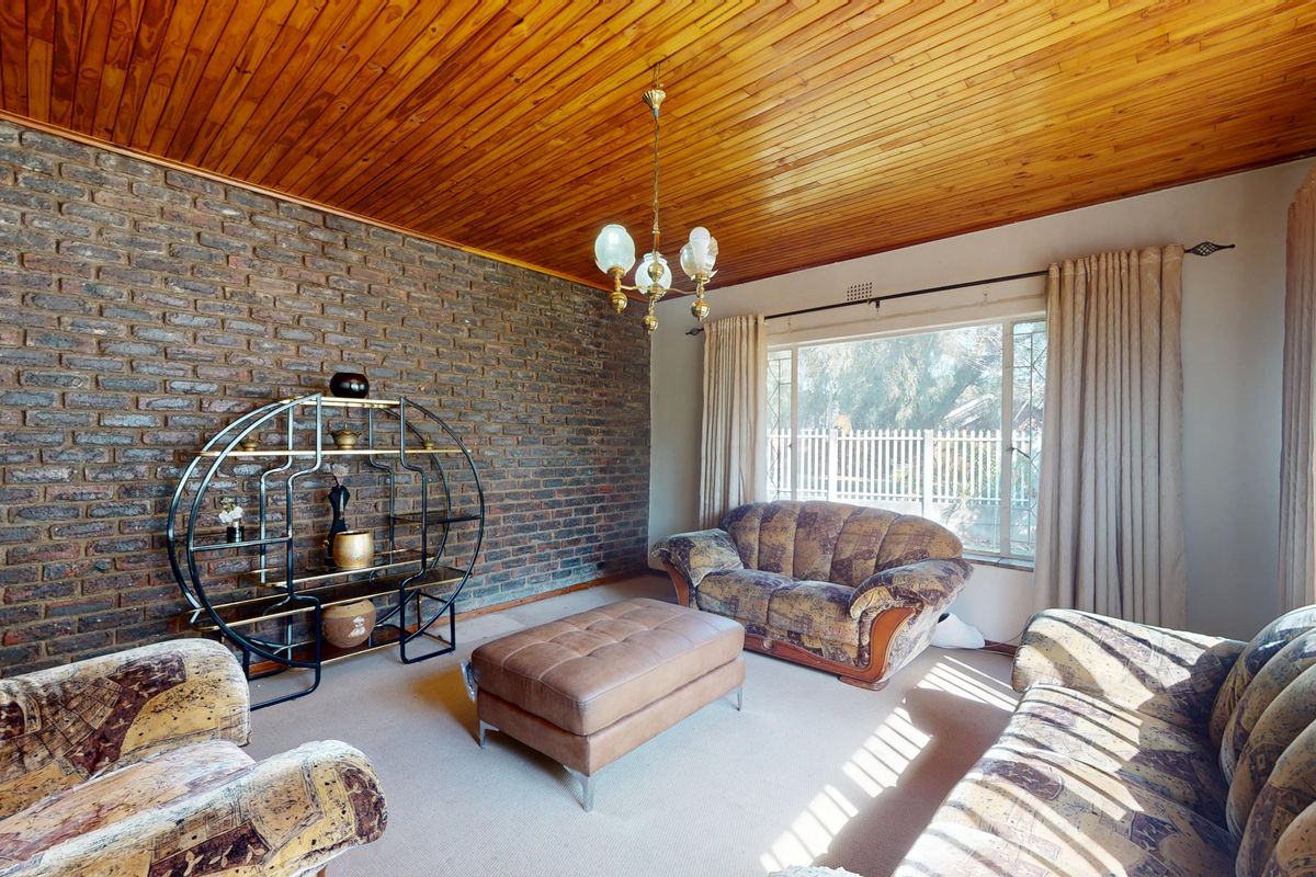 A living room featuring an exposed brick wall, timber ceiling, and large window providing natural light.