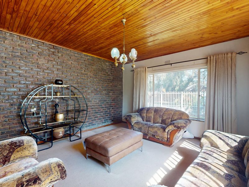A living room featuring an exposed brick wall, timber ceiling, and large window providing natural light.