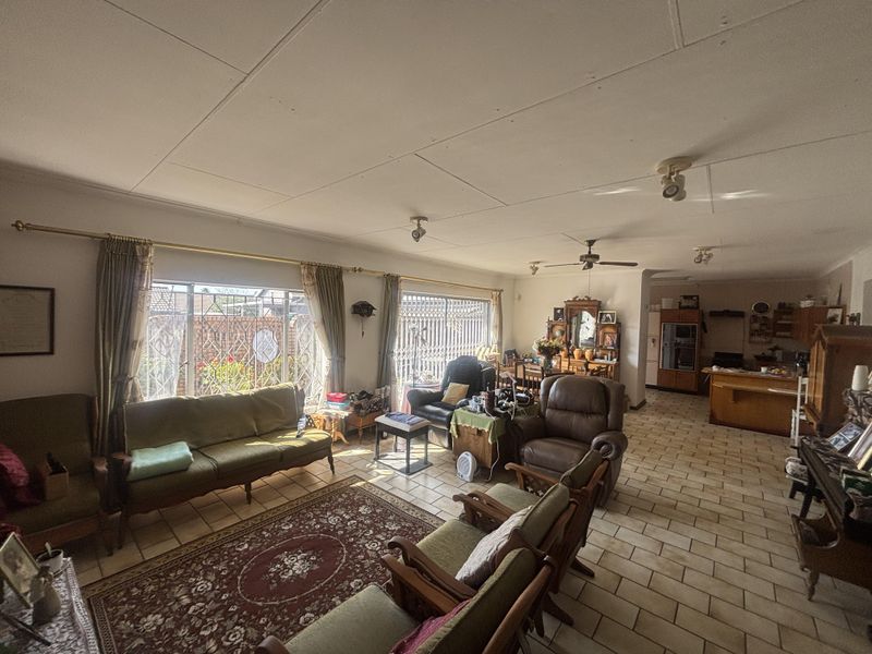 Spacious open-plan living and dining area featuring tiled flooring, ceiling fan, and direct access to the kitchen, offering significant potential for modernization.