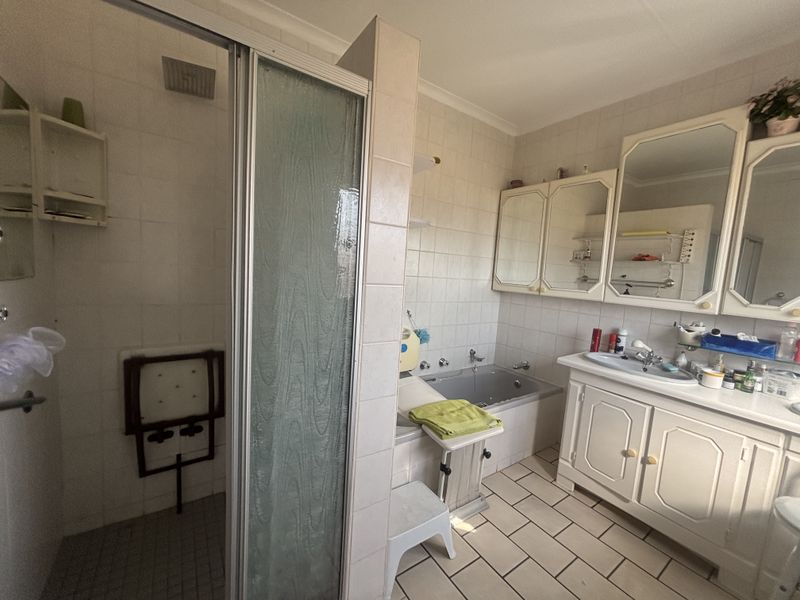 A functional bathroom featuring a separate shower enclosure, built-in bathtub, and a vanity unit with integrated storage and mirror cabinets.