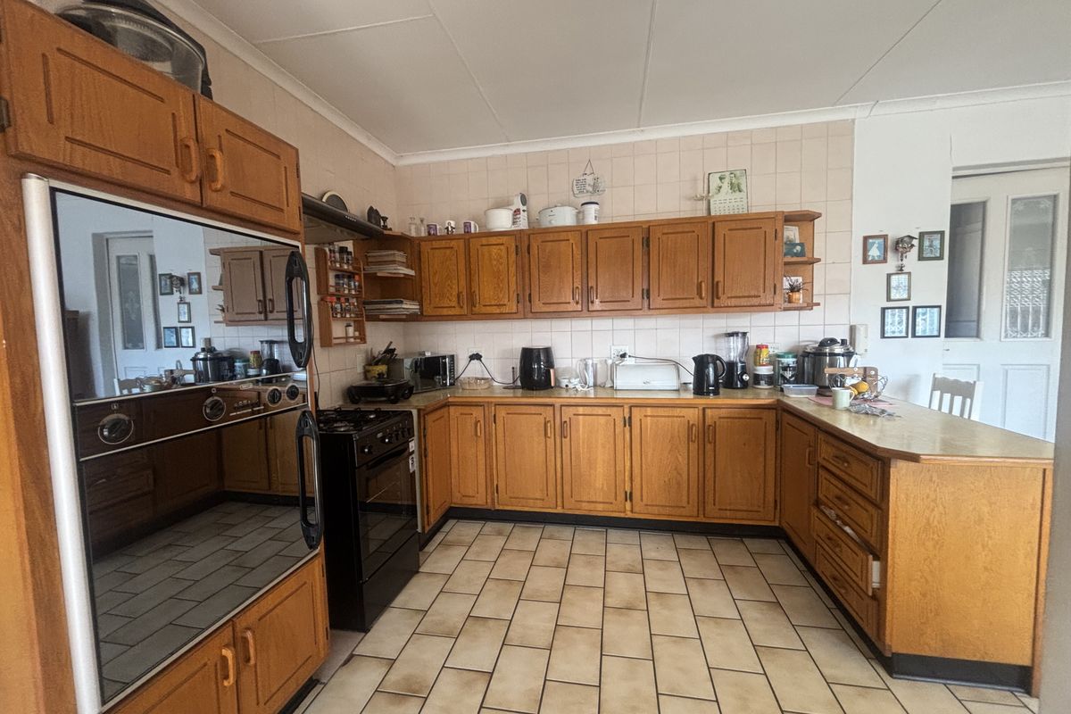 A functional kitchen featuring traditional wooden cabinetry, tiled backsplash, and tiled flooring, offering a classic layout with ample storage and counter space.