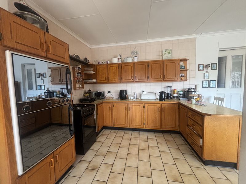 A functional kitchen featuring traditional wooden cabinetry, tiled backsplash, and tiled flooring, offering a classic layout with ample storage and counter space.