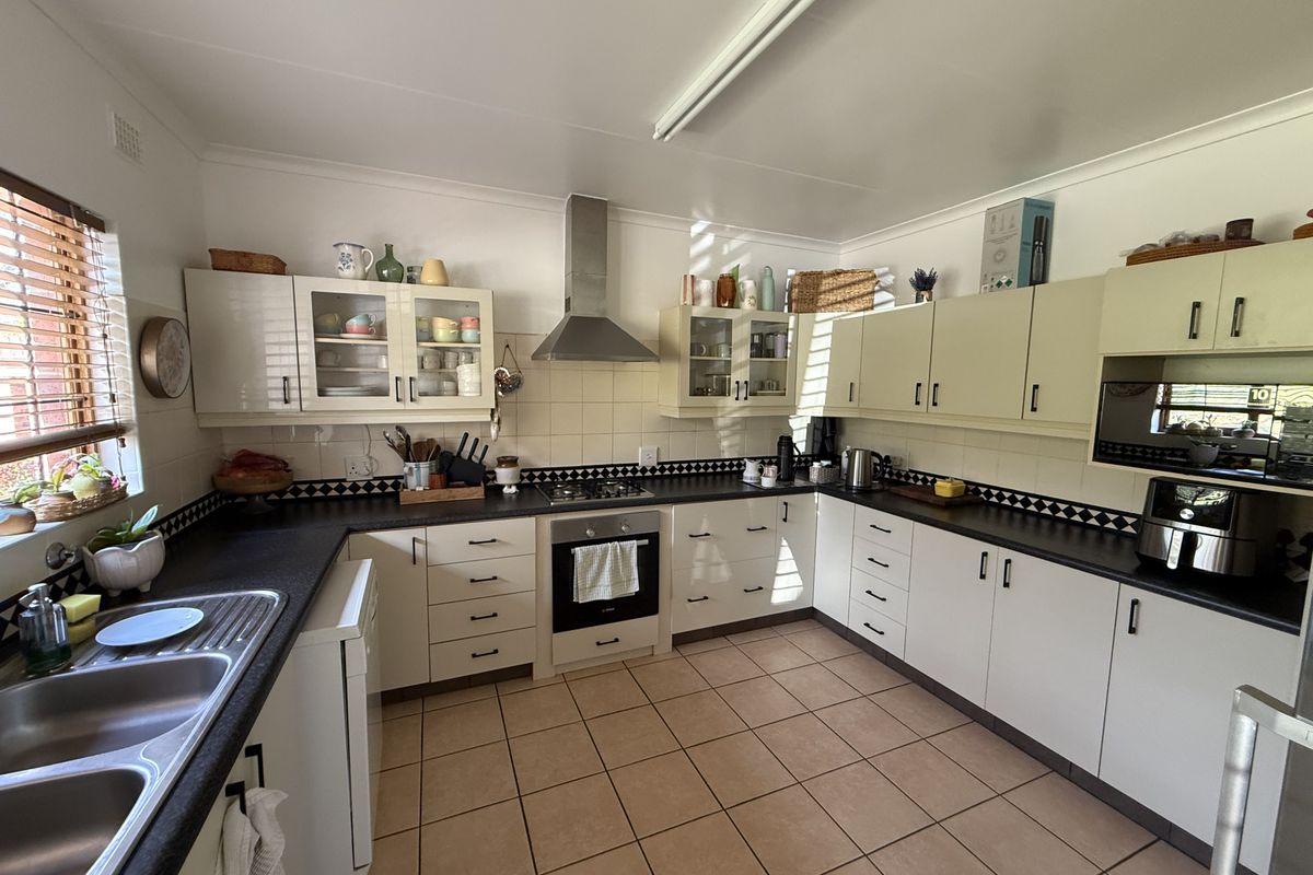 A functional U-shaped kitchen featuring ample built-in cabinetry, dark laminate countertops, a gas cooktop, and tiled flooring.
