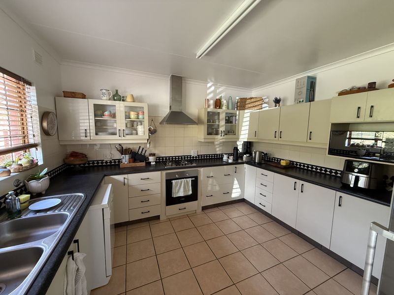 A functional U-shaped kitchen featuring ample built-in cabinetry, dark laminate countertops, a gas cooktop, and tiled flooring.