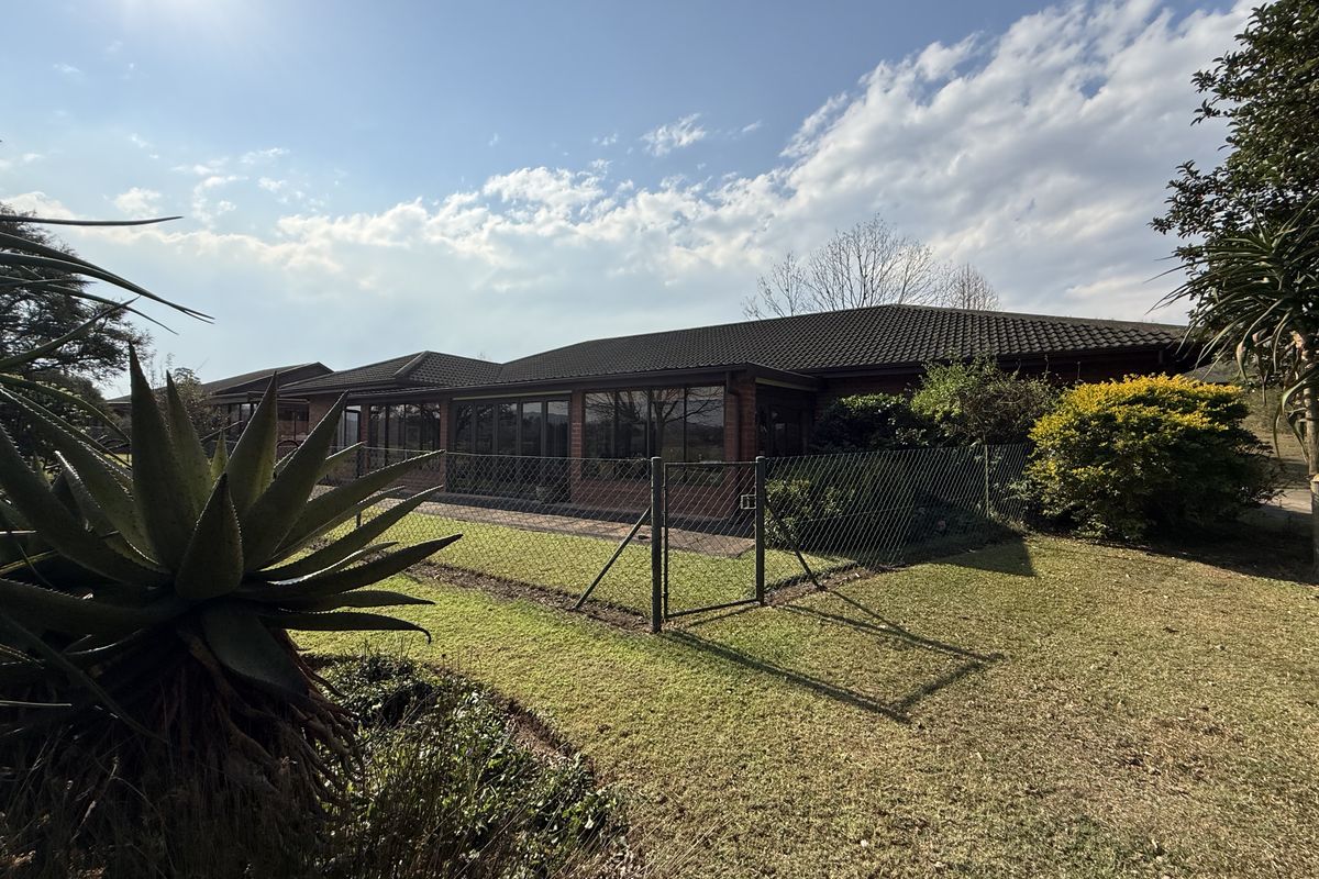 Rear view of the property featuring a brick facade, tiled roof, and a paved patio area accessible through large sliding glass doors.