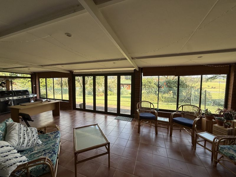 Spacious enclosed patio featuring tiled flooring, exposed beam ceiling, and large bi-fold doors providing seamless access to the garden.
