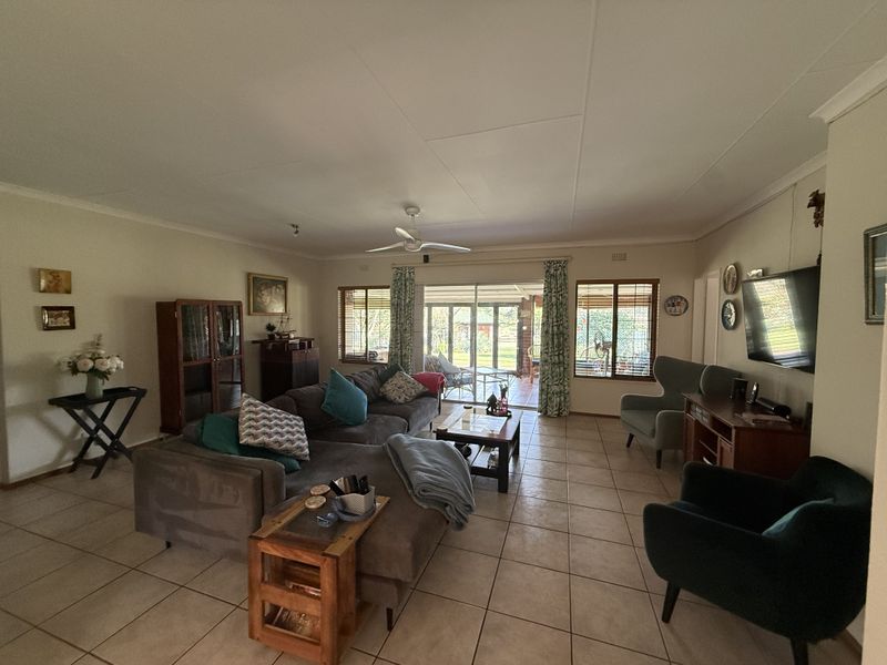 Spacious living room featuring neutral tiled flooring, a ceiling fan, and large sliding glass doors providing natural light and access to the outdoor patio area.