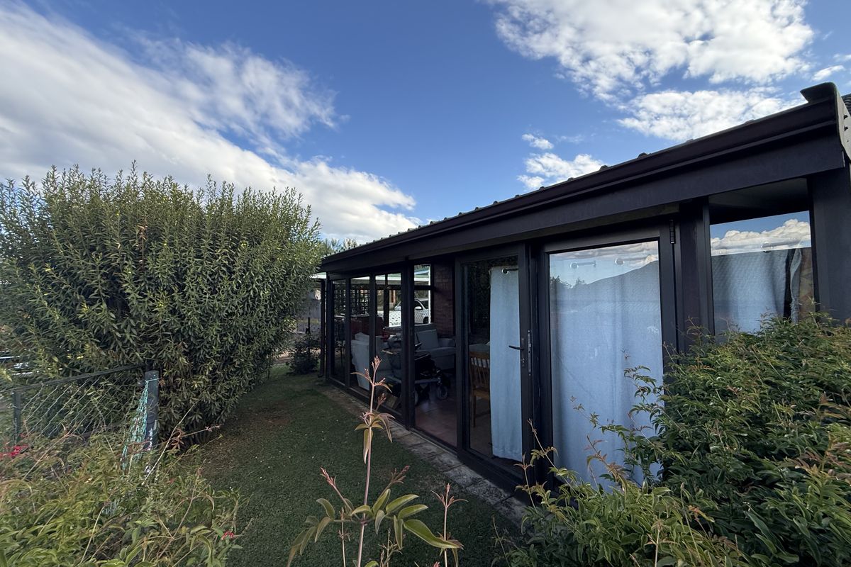Rear view of the townhouse featuring a modern enclosed patio area with large sliding glass doors and a well-maintained garden.