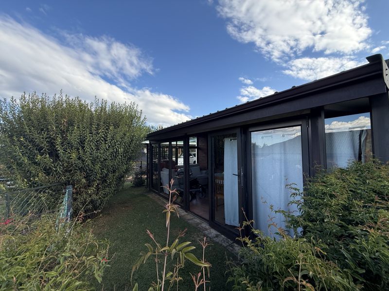 Rear view of the townhouse featuring a modern enclosed patio area with large sliding glass doors and a well-maintained garden.