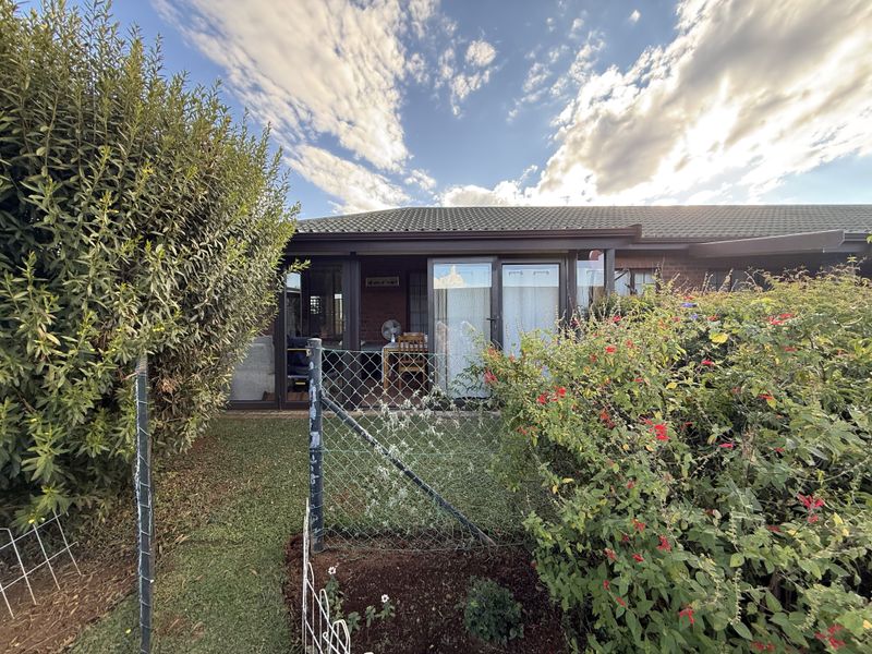 Rear view of the townhouse featuring a covered patio, sliding glass doors, and a private garden area enclosed by chain link fencing.