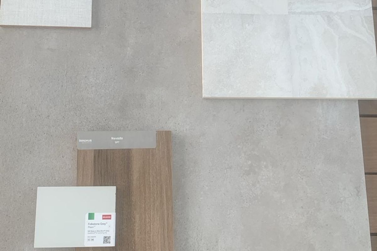 A collection of material samples including stone-look tiles, wood-grain laminate, and textile swatches for interior design planning.