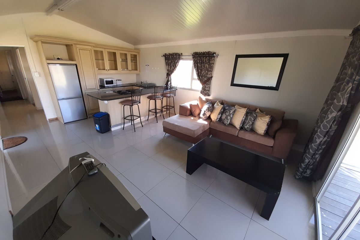 Open-plan living area featuring a kitchen with built-in cabinetry and island, tiled flooring, and direct access to an outdoor space via sliding doors.