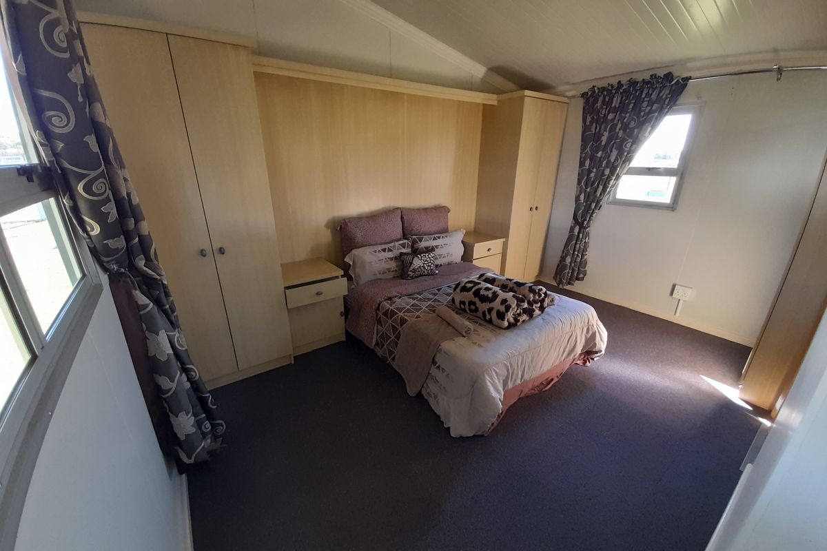 A bedroom featuring built-in wardrobes and integrated bedside cabinetry with neutral wall finishes and carpet flooring.