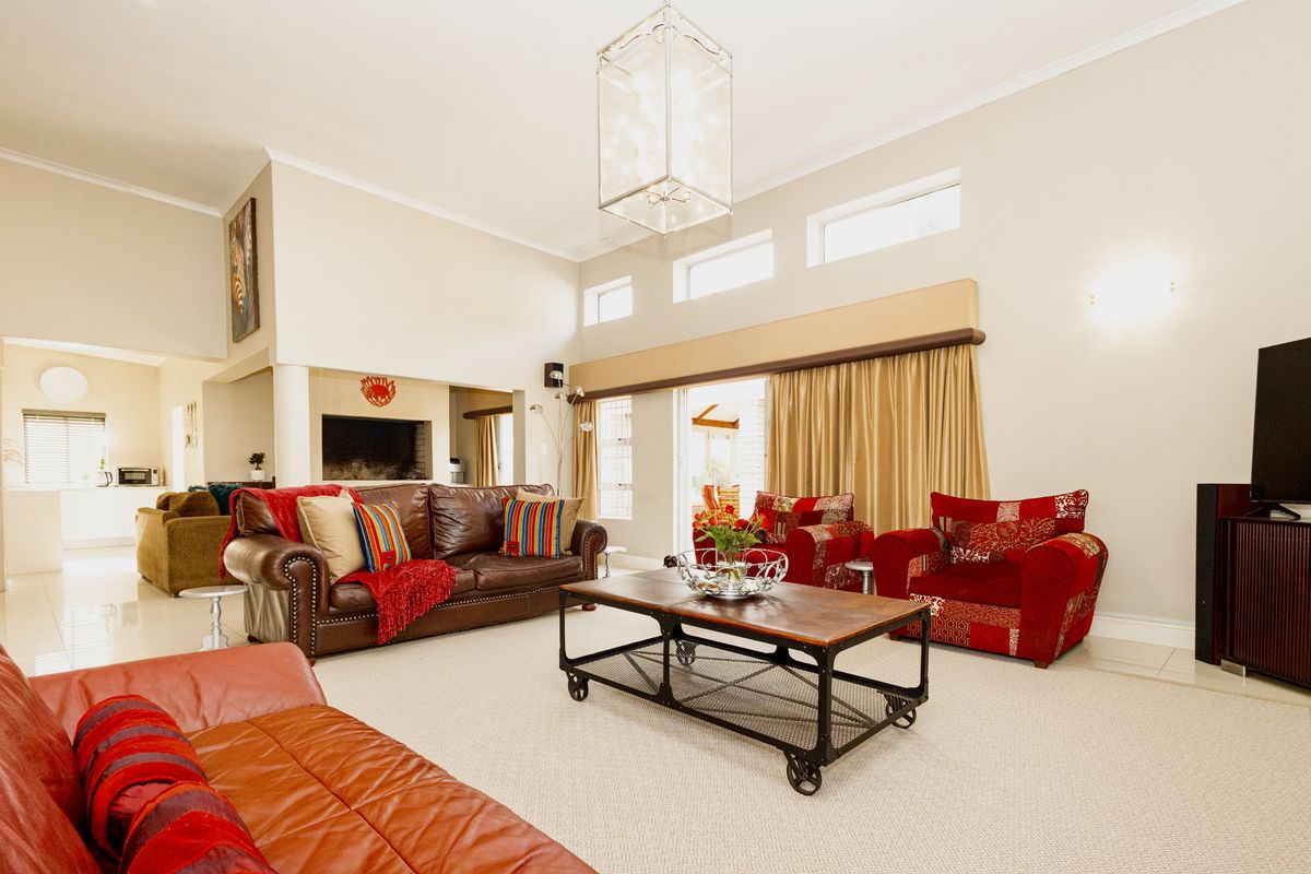 Spacious living room featuring high ceilings, large pendant lighting, tiled floors, and sliding glass doors leading to an outdoor area.