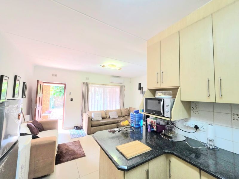 Open-plan living area featuring a functional kitchen with granite countertops and built-in cabinetry, flowing into a lounge space with direct access to the exterior.
