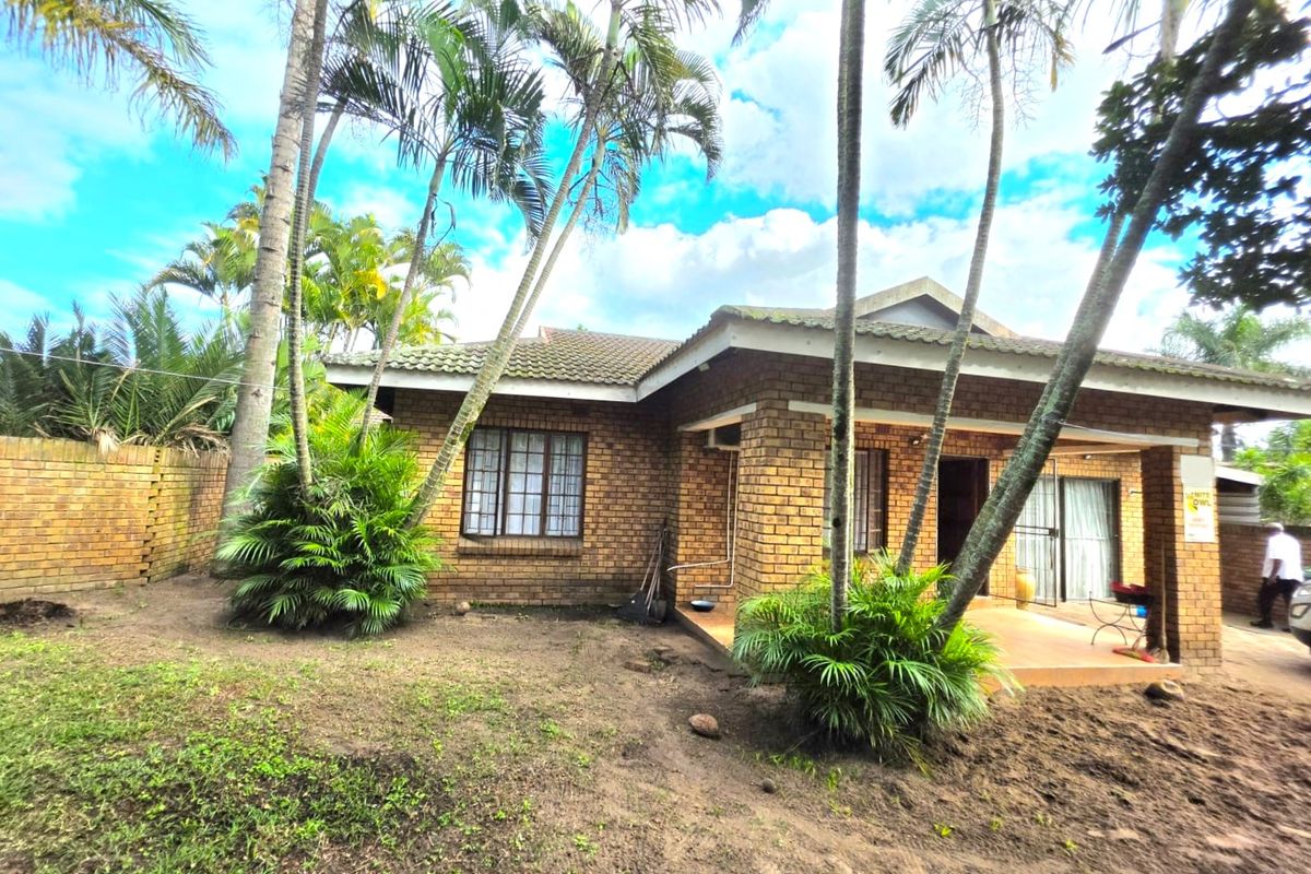 Rear view of a face brick duet property featuring a covered patio, tiled roof, and established garden area.