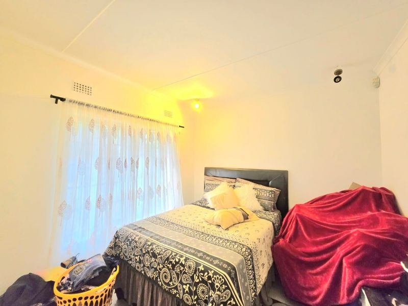 A standard bedroom featuring white walls, a curtain rail, and ventilation bricks, providing a functional space for rest.