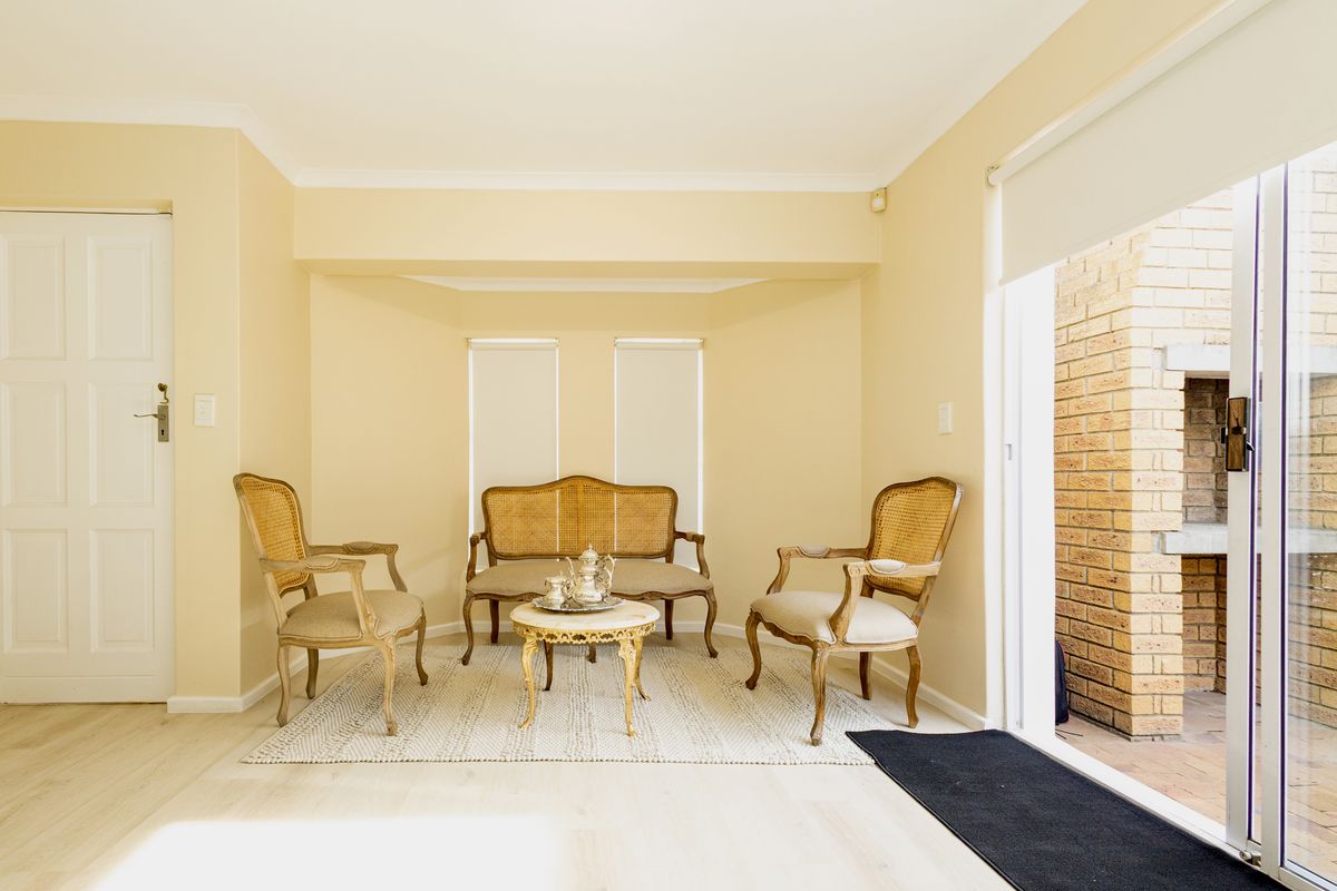 A bright living area featuring a bay window, neutral walls, and a sliding glass door providing direct access to an outdoor patio space.