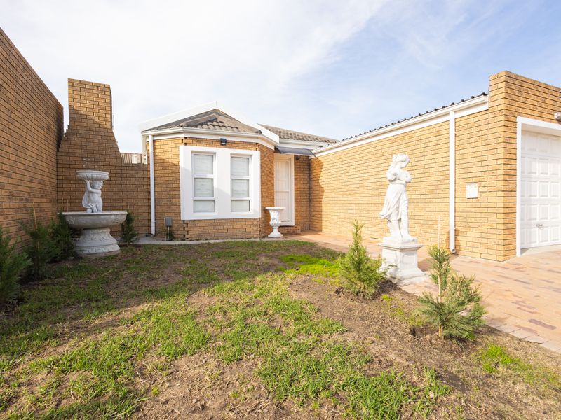 Front exterior view of a face brick townhouse featuring a paved driveway, single garage, and a small front garden area.