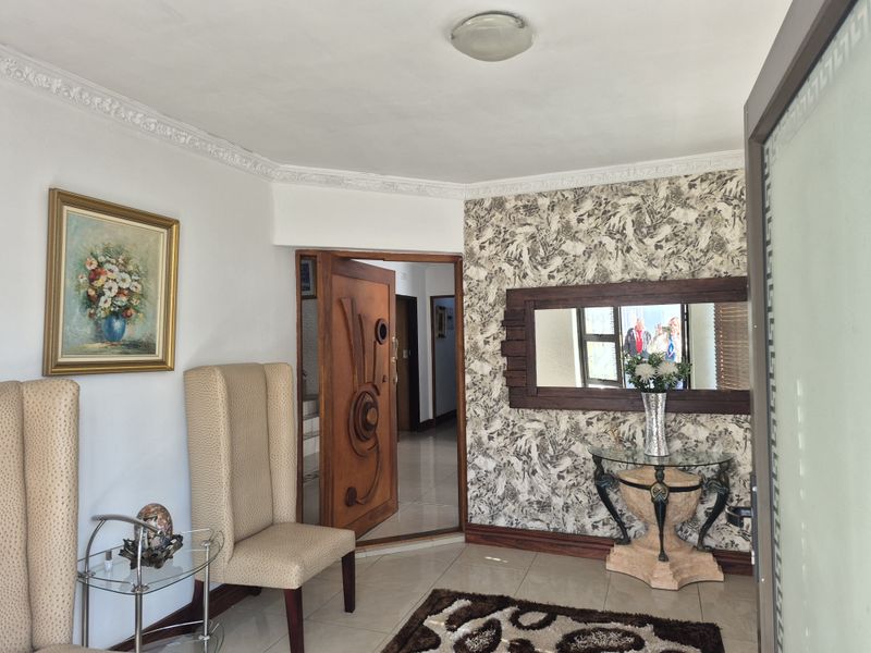 Welcoming entrance hall featuring tiled flooring, decorative ceiling cornicing, and a feature wall with patterned wallpaper.