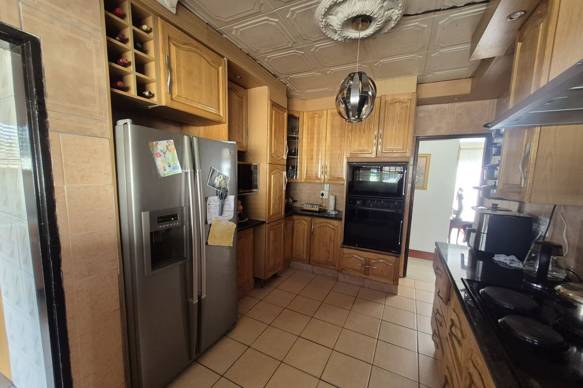 A functional kitchen featuring wooden cabinetry, built-in appliances, tiled flooring, and decorative ceiling tiles, offering a traditional layout with ample storage space.