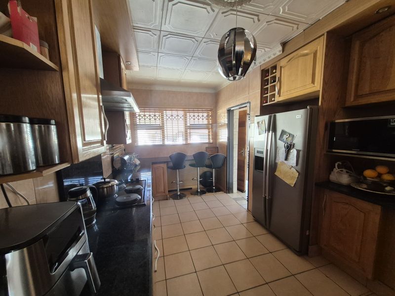 A functional kitchen featuring wooden cabinetry, granite countertops, built-in appliances, and decorative ceiling tiles, offering a classic layout with ample storage space.