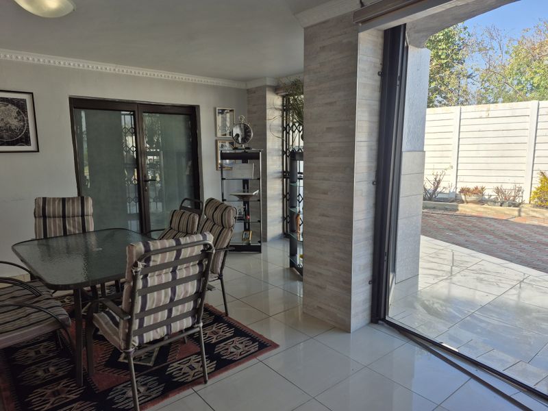 A covered patio area featuring tiled flooring, a stone-clad pillar, and large sliding glass doors that provide seamless access to the outdoor space.