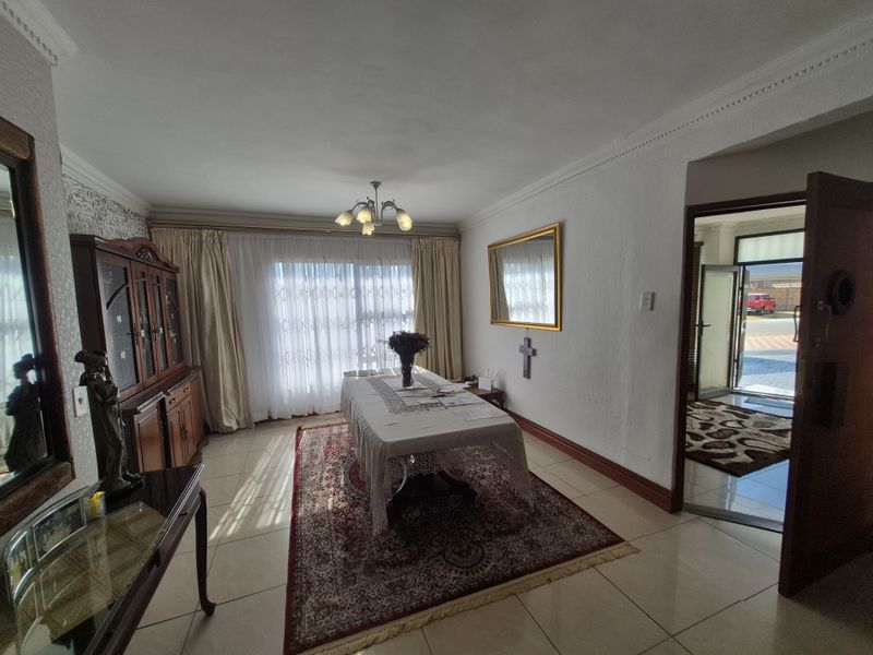 A dining room featuring tiled flooring, decorative ceiling cornicing, and a central chandelier, with direct access to the entrance area.