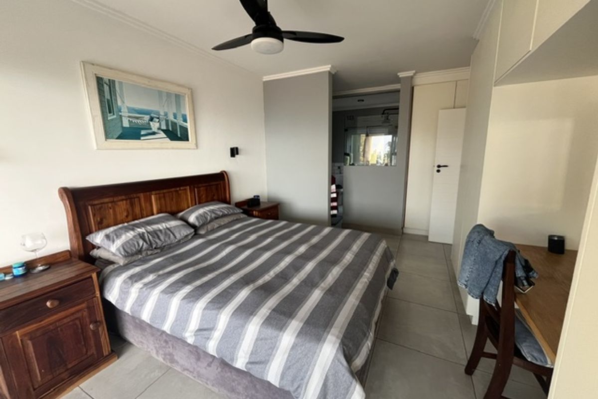 Spacious bedroom featuring tiled flooring, a ceiling fan, and convenient access to an en-suite bathroom with built-in storage.