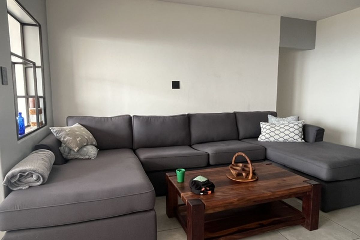 A comfortable living room area featuring neutral wall finishes, tiled flooring, and a unique internal window feature.