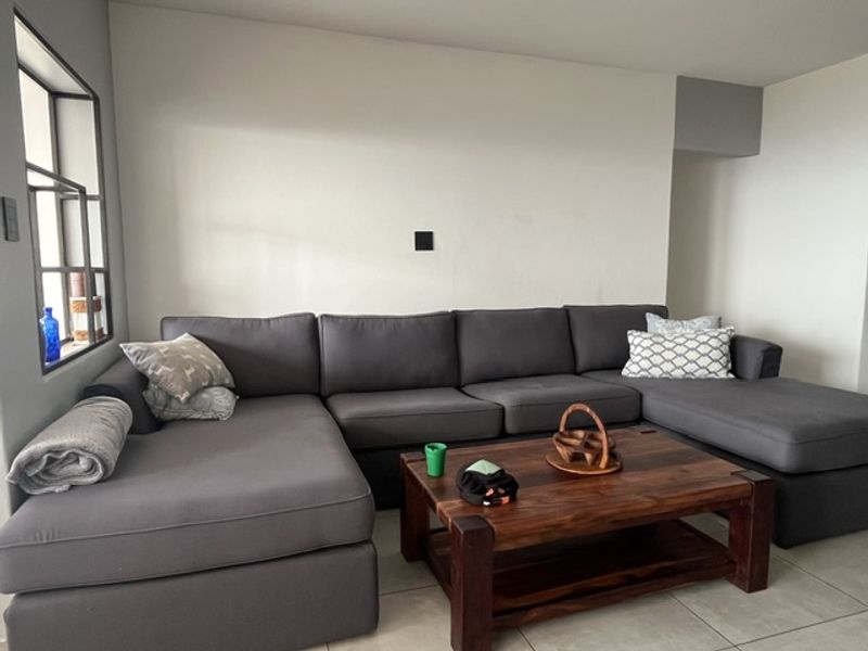 A comfortable living room area featuring neutral wall finishes, tiled flooring, and a unique internal window feature.