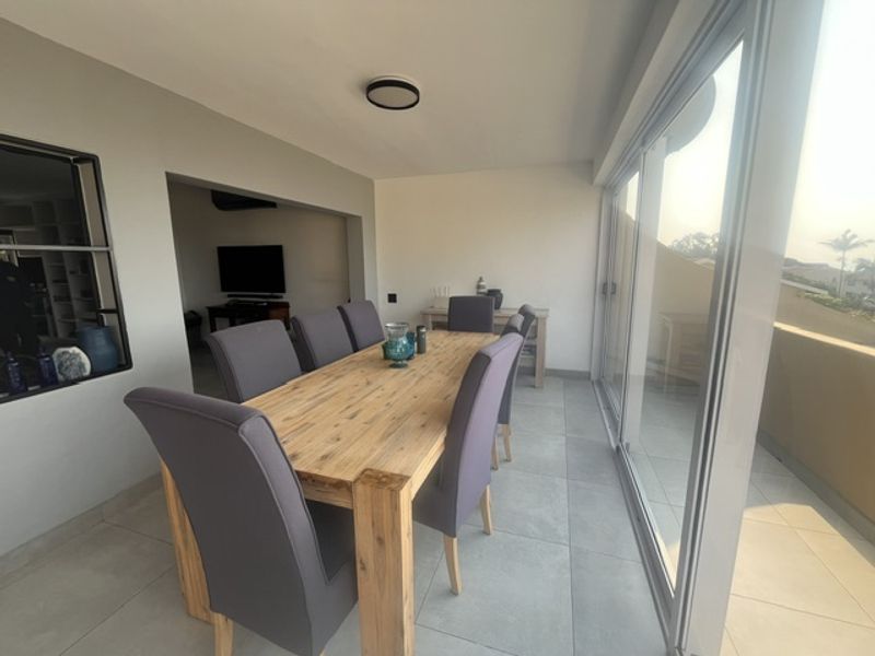 A bright dining area featuring large format floor tiles and expansive sliding glass doors that provide natural light and access to the outdoor space.