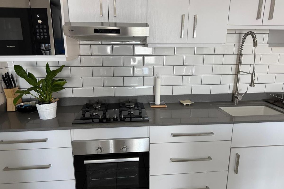 Modern kitchen featuring white cabinetry, quartz countertops, subway tile backsplash, and integrated Bosch appliances including a gas hob, oven, and microwave.