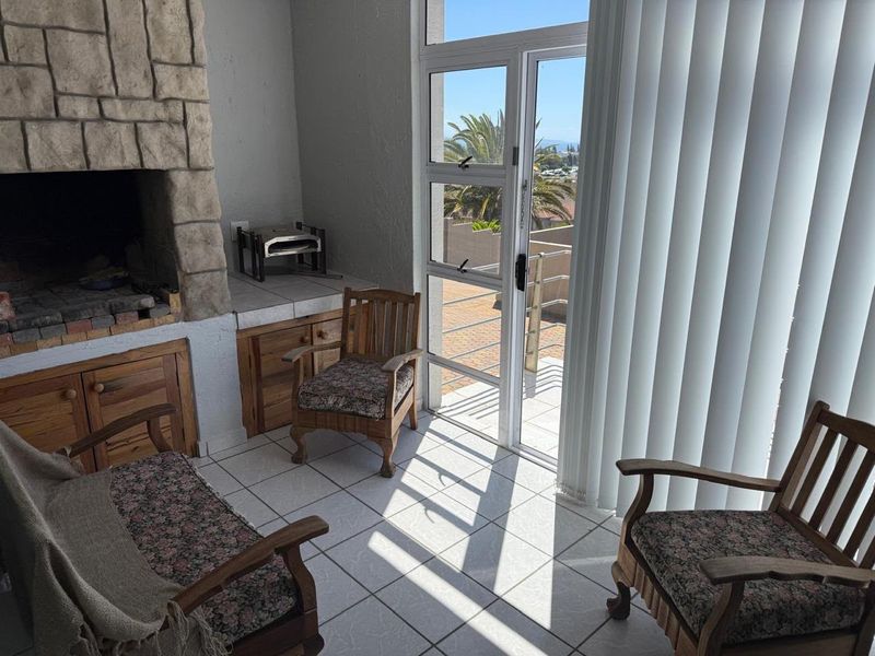 Covered balcony area featuring a built-in stone braai, tiled flooring, and direct access to an outdoor terrace through a glass sliding door.