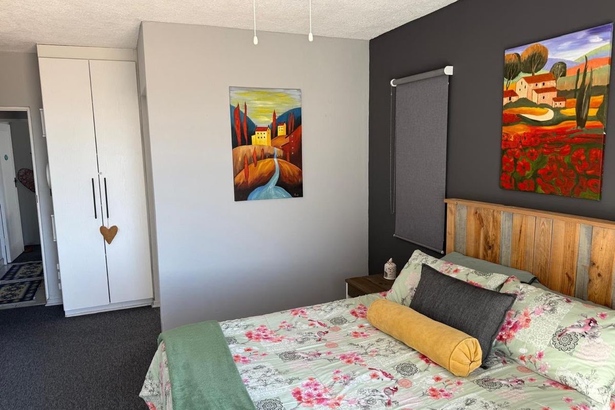 A well-maintained bedroom featuring a built-in wardrobe, ceiling fan, and a modern dark accent wall.