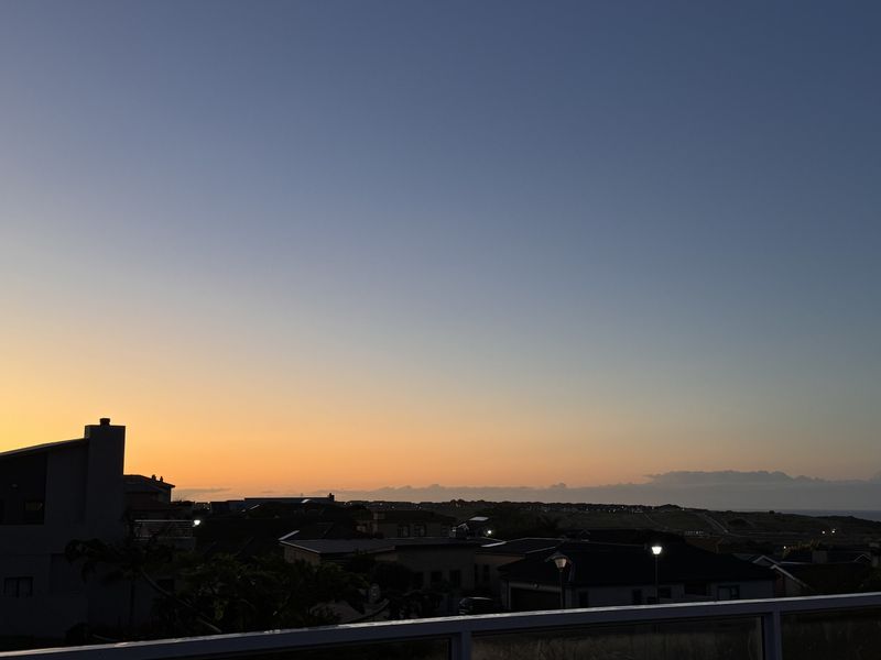 A scenic sunset view overlooking the surrounding residential neighbourhood, captured from an elevated position with a glass balustrade in the foreground.