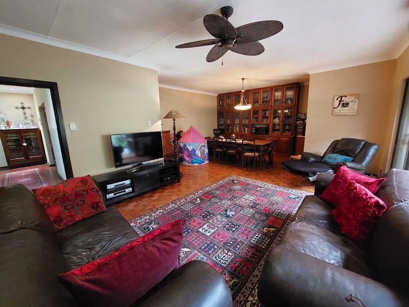 Spacious open-plan living and dining area featuring classic parquet flooring, a ceiling fan, and extensive built-in wooden cabinetry for storage.