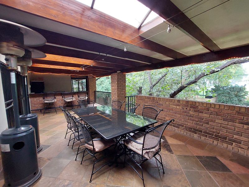 Spacious covered patio featuring exposed timber beams, a skylight, brick accents, and a built-in bar area, perfect for outdoor entertaining.