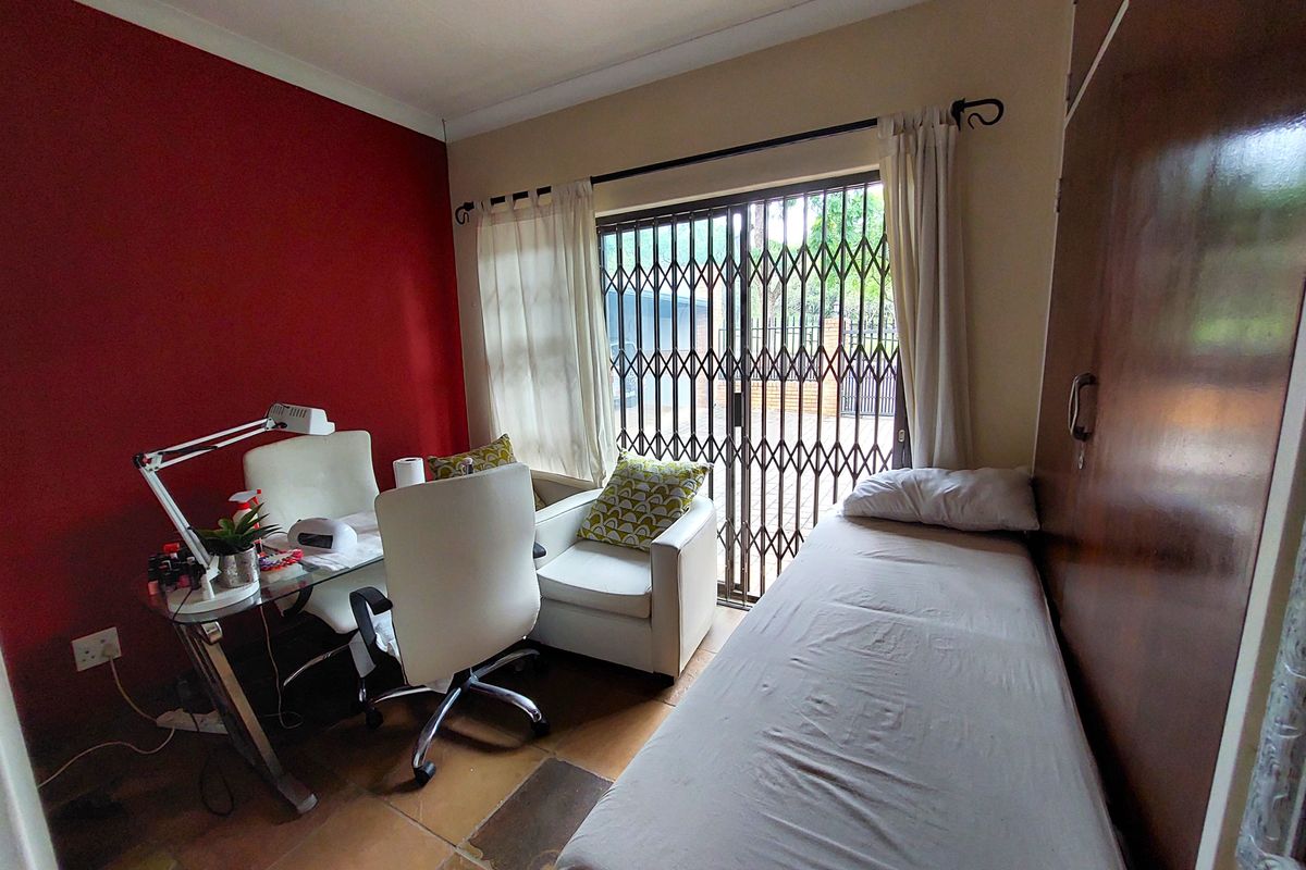 A bedroom featuring tiled flooring, a built-in wardrobe, and a sliding door with a security gate leading to the exterior.